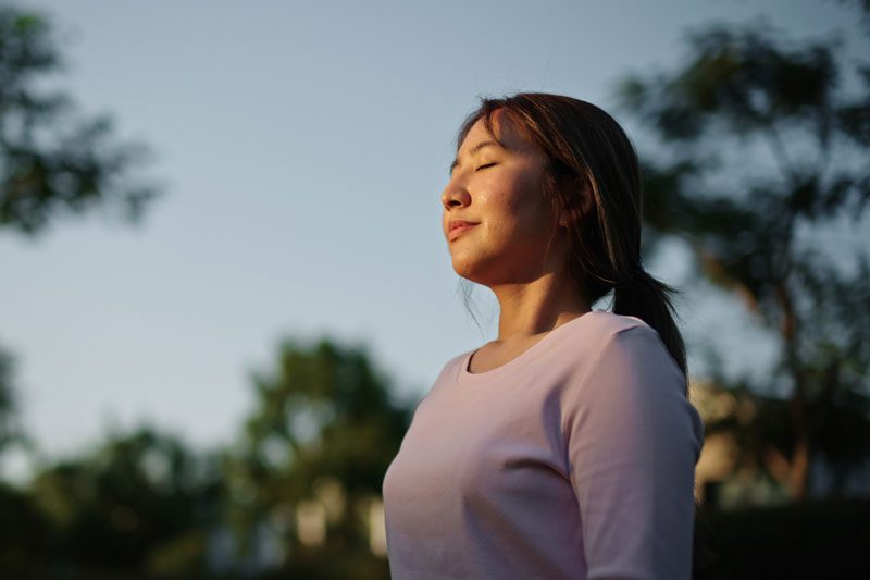 woman relaxing in nature - staying grounded to keep in the present moment