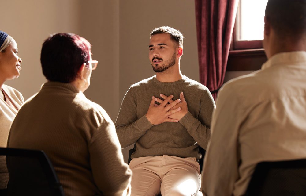 Diverse group of people sitting in a circle during a group therapy session, listening and sharing in a supportive environment. Intensive Outpatient Program IOP - Partial Hospitalization Program - PHP