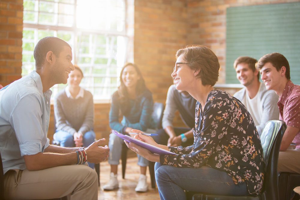 Diverse group of people sitting in a circle during a group therapy session, listening and sharing in a supportive environment. Intensive Outpatient Program IOP - Partial Hospitalization Program - PHP