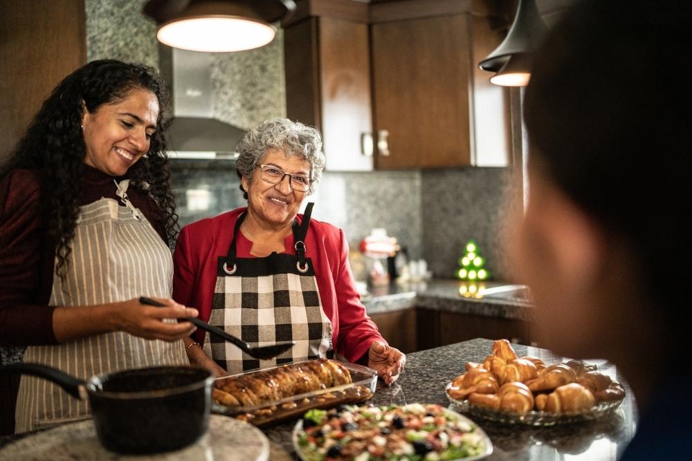 Mother and daughter talking while preparing food at kitchen counter at home